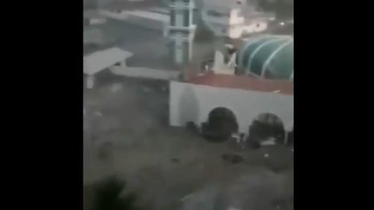 A tsunami wave floods a mosque in the town of Palu. 