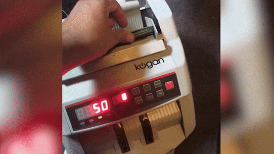 Fugitive ICAC suspect Ibrahim Helmy counts $100 notes in a money machine.