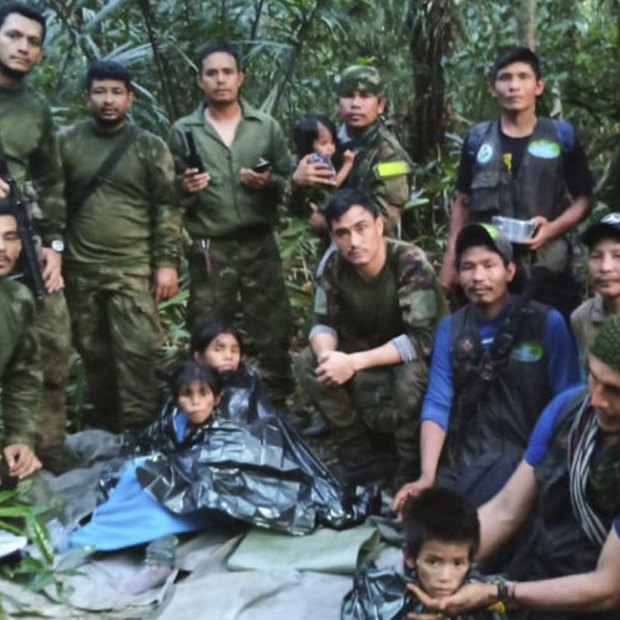 In this photo released by Colombia’s Armed Forces Press Office, soldiers and indigenous men pose for a photo with the four indigenous children who were missing after a deadly plane crash.