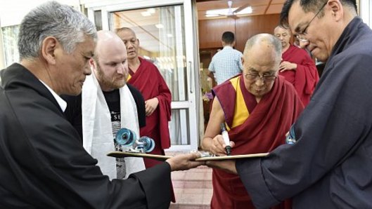 The Dalai Lama signs Aleks Stocki's skateboard.