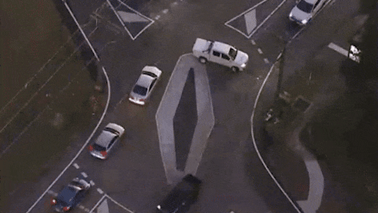 Aerial footage shows a ute doing a three-point turn to get around the diamond, while two other cars cut directly across the roundabout.