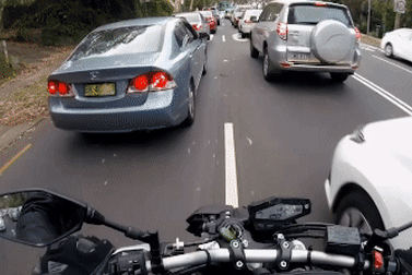 A motorbike rider lane splitting. 