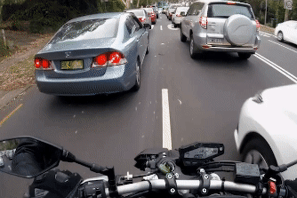 A motorbike rider lane splitting. 