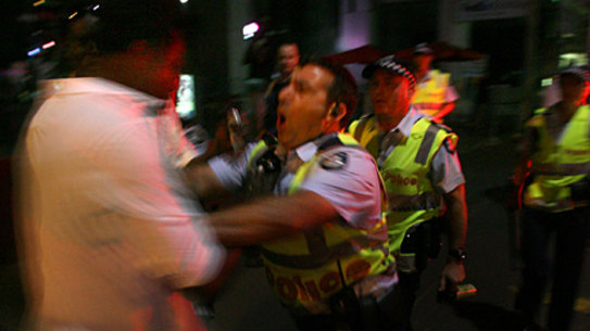 Police form a line with batons to move on a group of people outside a bar on Bourke Street.