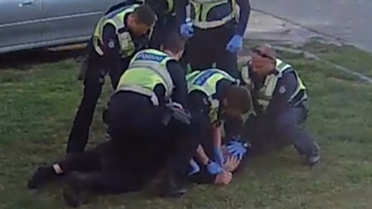 An image from CCTV footage showing police pinning pensioner John to the ground.