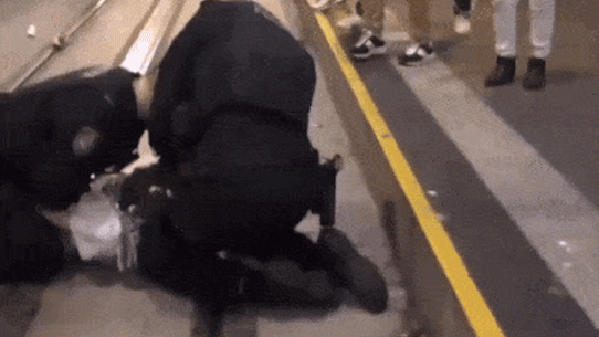 Um policial se ajoelha sobre uma pessoa durante um protesto no CBD de Sydney, enquanto outro policial dá socos repetidos.