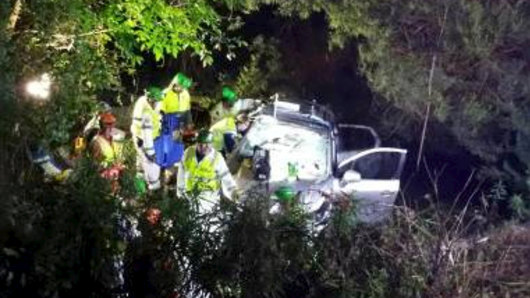 Emergency crews work together to free a woman trapped in an overturned vehicle at Kianga.