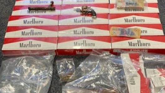 Illicit cigarettes worth $15,000, cash, drugs and guns were found in the raid.