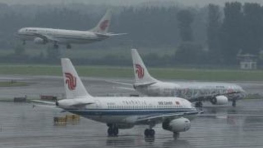 An Air China passenger plane lands while two other Air China planes wait to take off at Beijing International Airport.