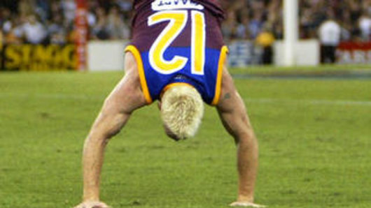 Jason Akermanis celebrating a  win with his trademark hand stand.