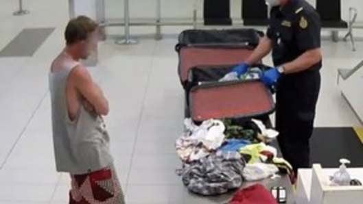 A customs officer inspects the man's bags at Gold Coast Airport on Saturday.