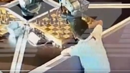 A chess-playing robot grabs hold of a child’s finger.