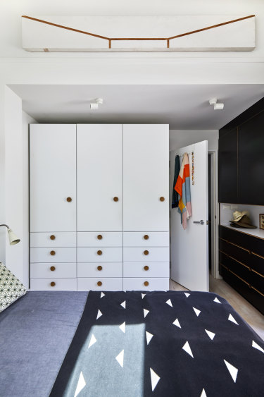 The main bedroom has dual ceiling heights, creating a sense of space. Ruth offsets the white tones with colourful scarves. The artwork is by Jas Hugonnet.