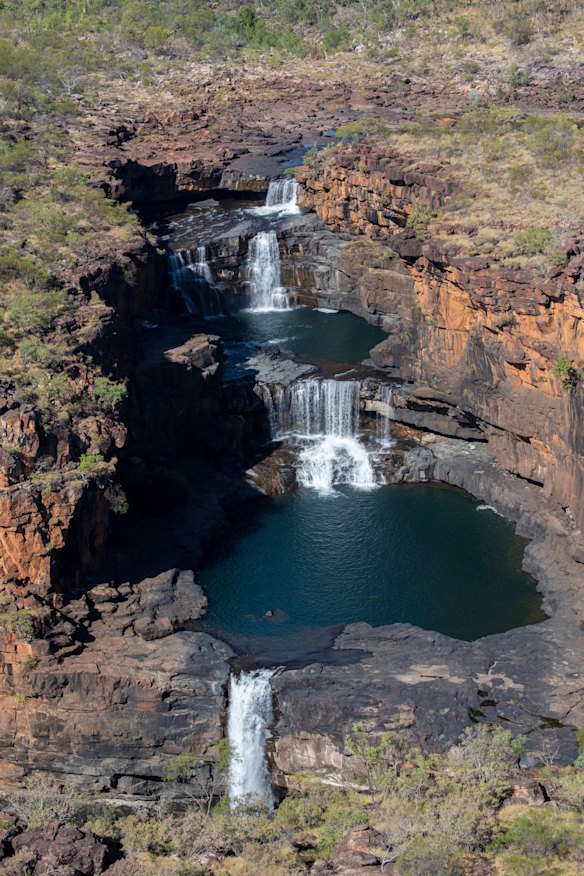 A helicopter joy flight performs two spectacular orbits of the Mitchell Falls before returning hikers to its base.