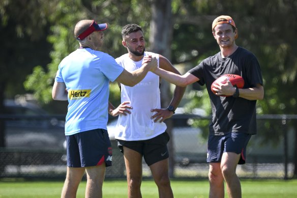 We’re back: Demons coach Simon Goodwin with premiership stars Christian Salem and Bayley Fritsch at training on Monday.