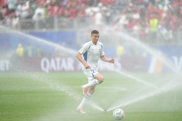 Uzbekistan's Avazbek Ulmasaliyev (25) runs to avoid water from the pitch sprinklers after the first half of the World Cup Group K soccer match between Portugal and Uzbekistan in Houston.