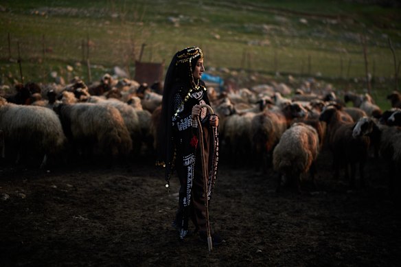 Wearing a traditional dress, Parzhin Jasem, poses for a photo next to sheep belonging to her uncle as she takes part in a family gathering to break the fast with an Iftar meal during the Muslim holy month of Ramadan in the village of Gulp, Iraq.
