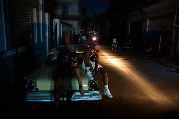 Men sit on the trunk of a car during a blackout in Havana, Cuba.