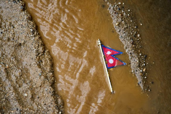 A Nepal flag lies on a muddy track near the banks of the Trishuli river in Dhading District, Nepal.