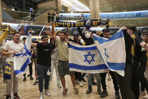 People welcome Maccabi Tel Aviv soccer fans as they arrive at Israel’s Ben-Gurion International Airport on a flight from Amsterdam, where Israeli soccer fans were attacked.