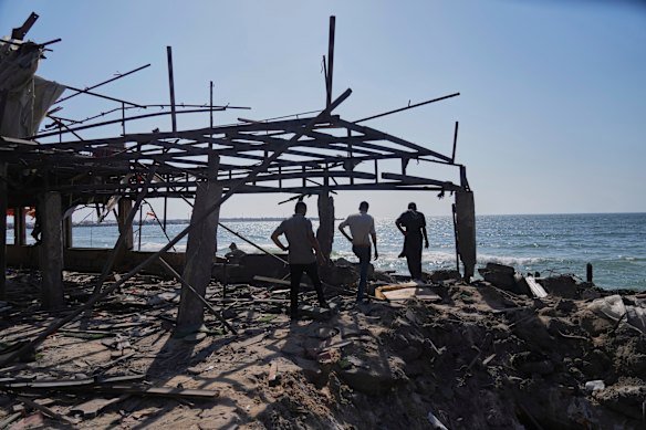 Palestinians walk through the ruins of a Gaza City cafe after it was hit by an Israeli airstrike on Monday.