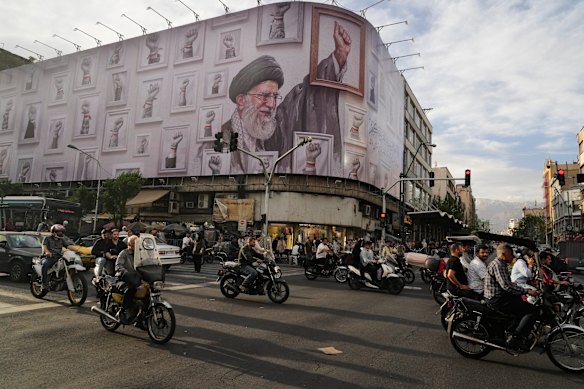 Motorbikes drive past a billboard showing the late Iranian Supreme Leader Ayatollah Ali Khamenei in downtown Tehran.