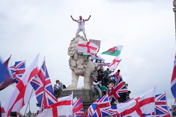 A demonstrator stands on the head of one of the lions of Westminster Bridge during the protest on Saturday.