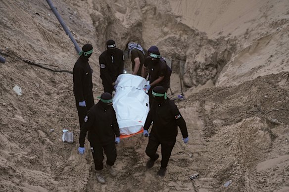 Hamas militants carry a white bag believed to contain a body, after retrieving it from a tunnel during a search for the remains of hostages in Hamad City, Khan Younis, in southern Gaza.