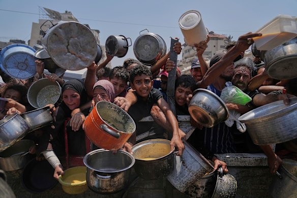 Palestinians struggle to get donated food at a community kitchen in Gaza City.