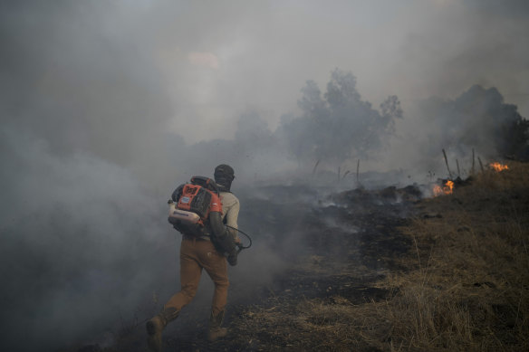 A ranger works to extinguish a fire after a rocket fired from Lebanon hit an open field in northern Israel.