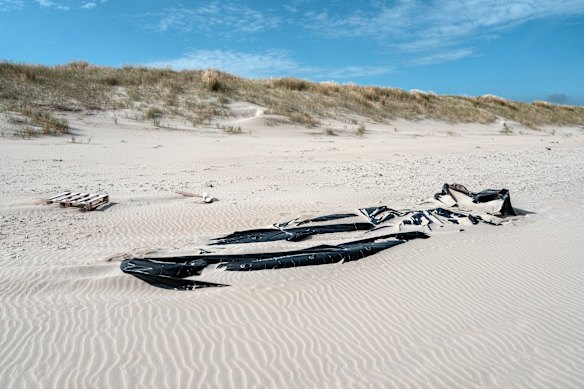 An abandoned dinghy lies in the sand on a beach known for cross channel migrant dinghy launches in Dunkirk, France.