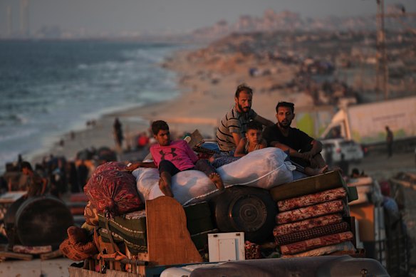 Displaced Palestinians flee Gaza City carrying their belongings along the coastal road toward southern Gaza.