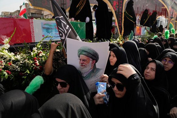 Mourners in Tehran gather around the flag-draped coffins of Iranians killed in Israeli strikes. One holds a poster of Ayatollah Ali Khamenei.