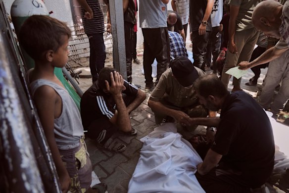 Mourners gather around the bodies of people killed while trying to reach aid trucks.