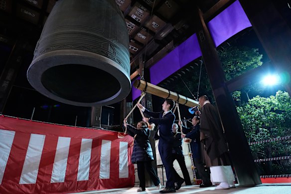 People strike a giant bell to celebrate the New Year at the Zojoji Buddhist temple in Tokyo.
