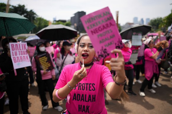 A protester in Jakarta on Wednesday applies lip balm while rallying against alleged police violence.