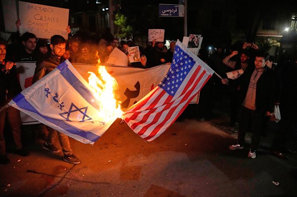 Pro-government protesters burn US and the Israeli flags in Tehran, Iran, on Wednesday, 