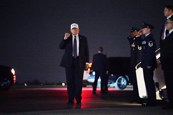 President Donald Trump holds up a fist after disembarking Air Force One at Palm Beach International Airport .