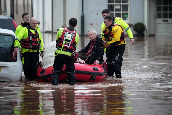Emergency services help people on a flooded street in Monmouth, Wales. 