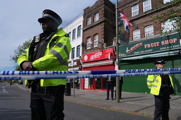 Police officers stand in the area where two people were stabbed in Golders Green.