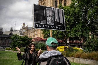 A protester holds a placard as he talks to a broadcast journalist on June 6 in England.