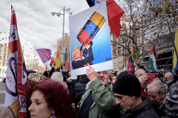 A protester outside the US embassy in Madrid holds a caricature of President Donald Trump drinking Venezuelan oil.