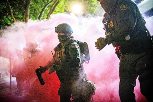 Police and federal officers throw gas canisters to disperse protesters near a US Immigration and Customs Enforcement facility in Portland, Oregon, on Sunday.