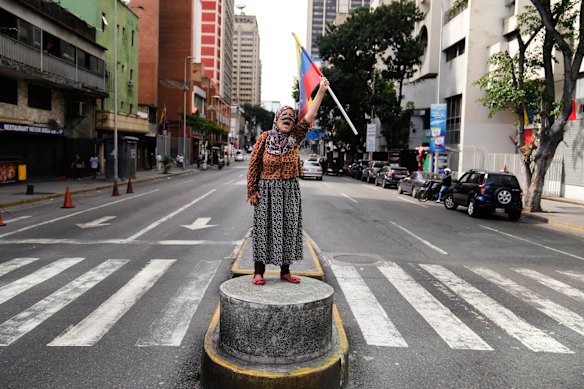 A supporter of Maduro stands on a median strip waving a national flag in Caracas on Saturday.