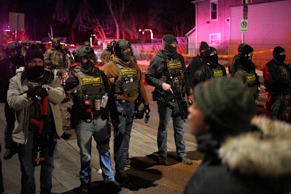 Federal law enforcement officers stand against protesters after a shooting in Minneapolis on Wednesday.