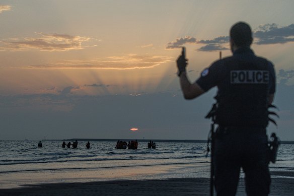 Oficiales de policía y películas como migrantes hasta el agua de las galicinas recolectadas por pequeños botes al sol.