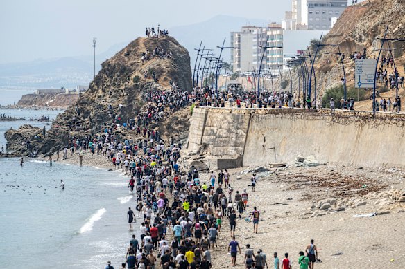 People walk on a beach after attempting to cross from Fnideq to Ceuta.