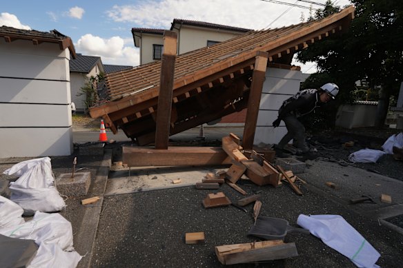 A man helps clean the damaged gate of Jofukuji Buddhist temple in Kumamoto.