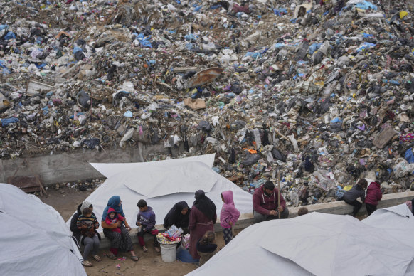 Palestinians displaced by the Israeli air and ground offensive sit in a makeshift tent camp inside a landfill in central Gaza Strip on Friday.