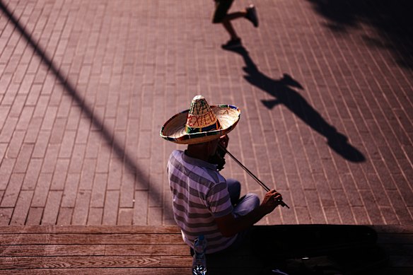 A street musician shelters with a hat against the sun as he performs for money during a hot day in Istanbul.